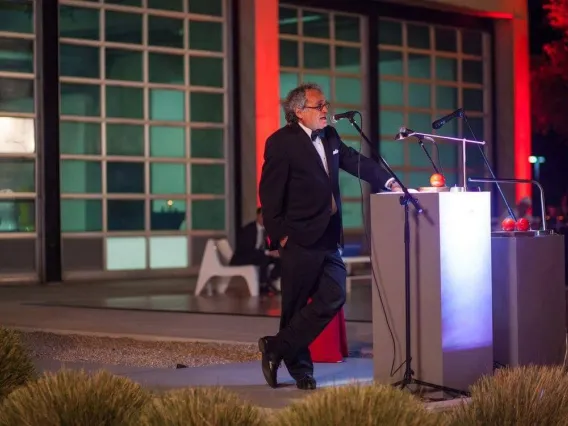 man standing at a podium outdoors at night