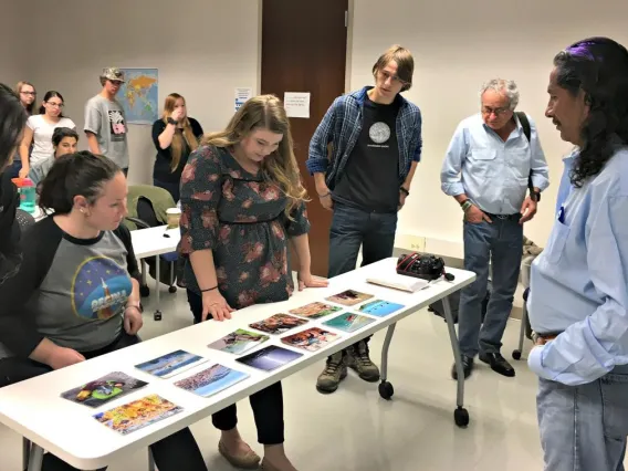 students looking down at a table with photos displayed