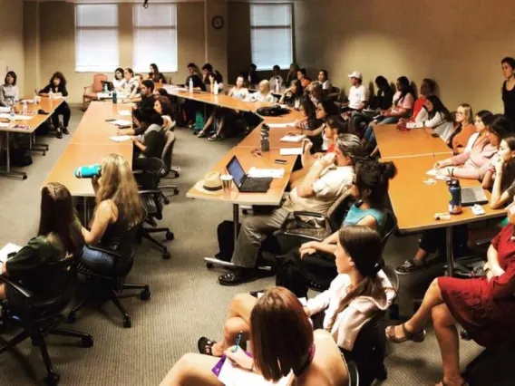 classroom filled with students, professor at the front speaking