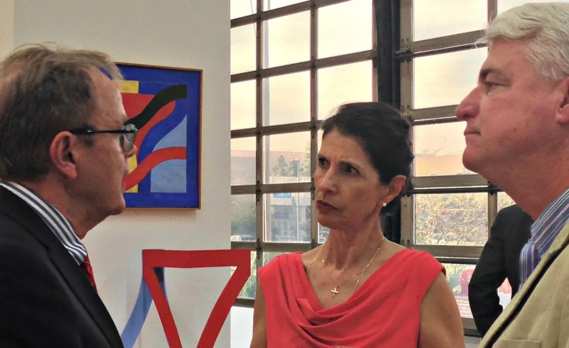 woman in red dress speaking with two men indoors