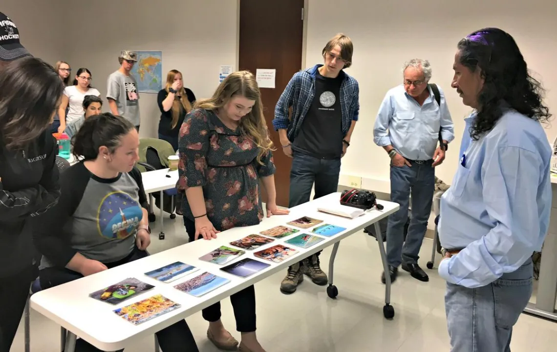 students looking down at a table with photos displayed