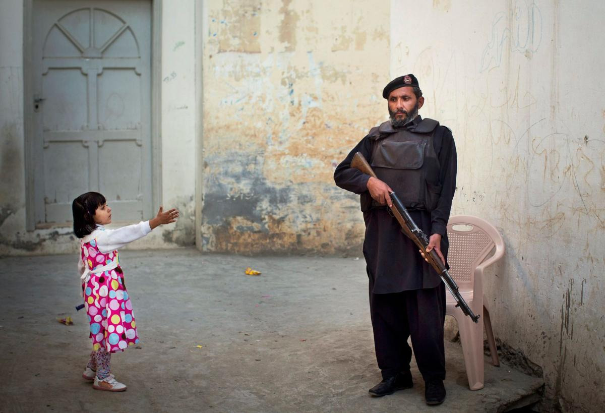 girl reaches out to a soldier in an alleyway of Afghanistan