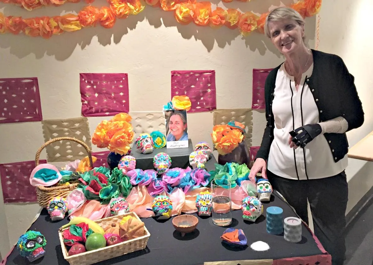 woman standing next to a Dia de los Muertos shrine and decorations