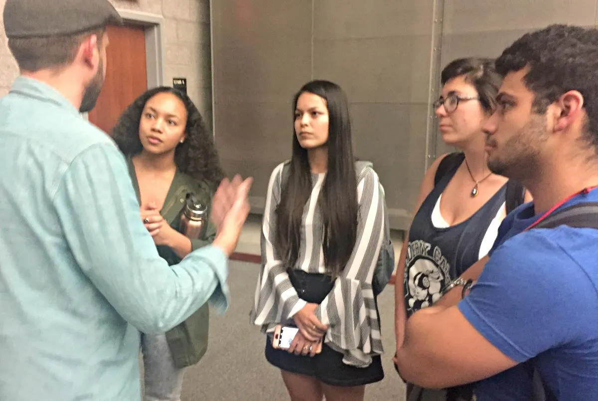 man talking to four students in a lecture room