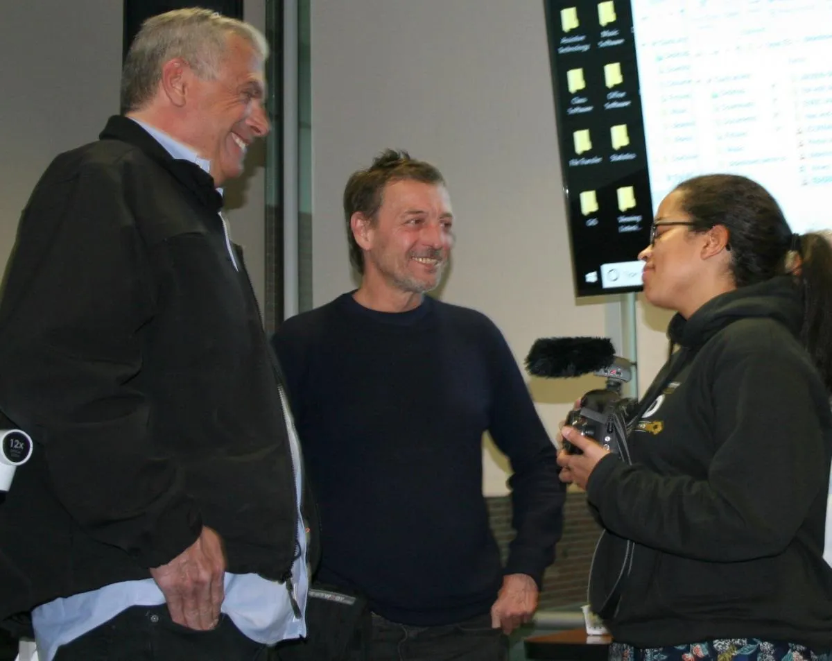 two men and a woman talking indoors