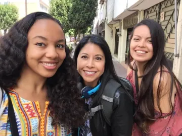 three women smiling, standing outdoors