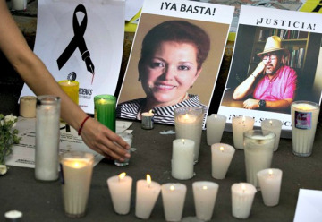 lit candles in the foreground with photos of a man and woman in the background