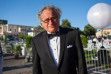 man in a tuxedo with grassy area and balloons behind